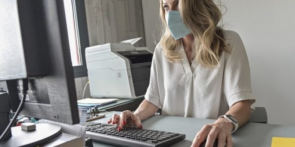 Executive woman working at her desk and wearing a protective mask against covid-19