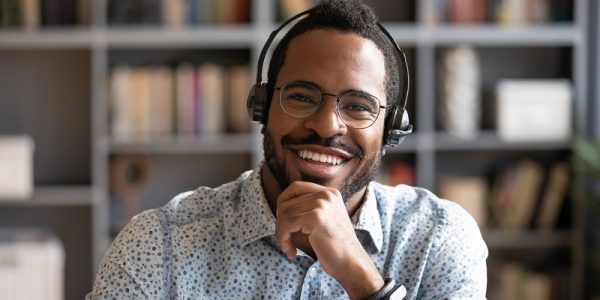 African man wear headset sit at desk looking at camera