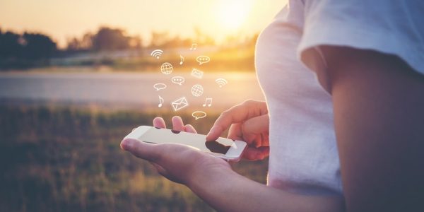 Woman Using smart phone emitting holographic image of social media