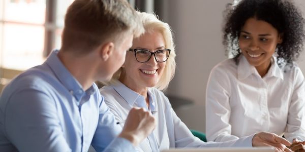 Smiling mature female mentor executive talking at diverse group meeting